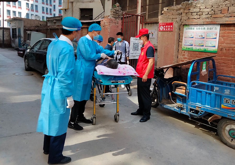 省司法厅下沉社区干部协助救护人员将一名急需就医的患者抬下楼，送往医院治疗。